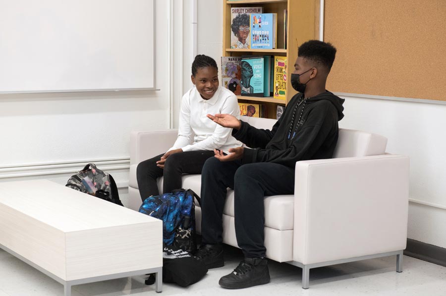 Two students are sitting and talking. Open Gallery